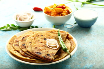 Indian vegetarian meal- homemade whole wheat aloo paratha served with potato curry and fresh raita