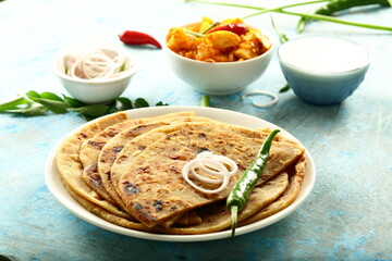 Indian vegetarian meal- healthy vegan diet - aloo paratha served with spicy potato curry and raita,.