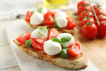Fototapeta na wymiar Delicious sandwiches with mozzarella, fresh tomatoes and basil on board
