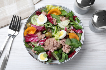 Bowl of delicious salad with canned tuna and vegetables served on white wooden table, flat lay