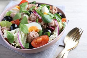 Bowl of delicious salad with canned tuna and vegetables served on white wooden table, closeup
