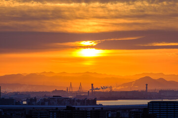 早朝、日が昇りあたりはオレンジ色に染まる。雲に隠れていた太陽が顔を出す。大阪湾の先に和泉山脈・紀伊山地の稜線が見える。