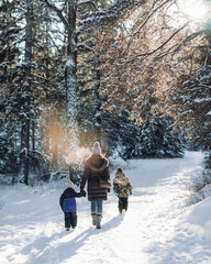 Woman and children walking along a snowy footpath in a forest