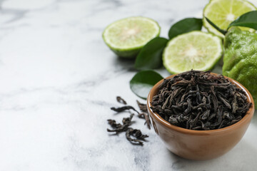 Dry bergamot tea leaves and fresh fruits on white marble table, space for text
