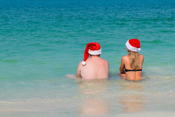 on the beach a fat man sits on the sea wearing a New Year's hat