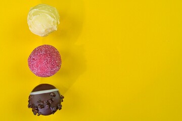 Chocolate bonbons or pralines on yellow pastel background. Chocolate pralines on yellow background...