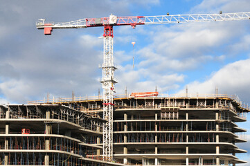 Multi-story commercial building under construction with tower crane overhead, illustrating structural development and large-scale urban infrastructure projects