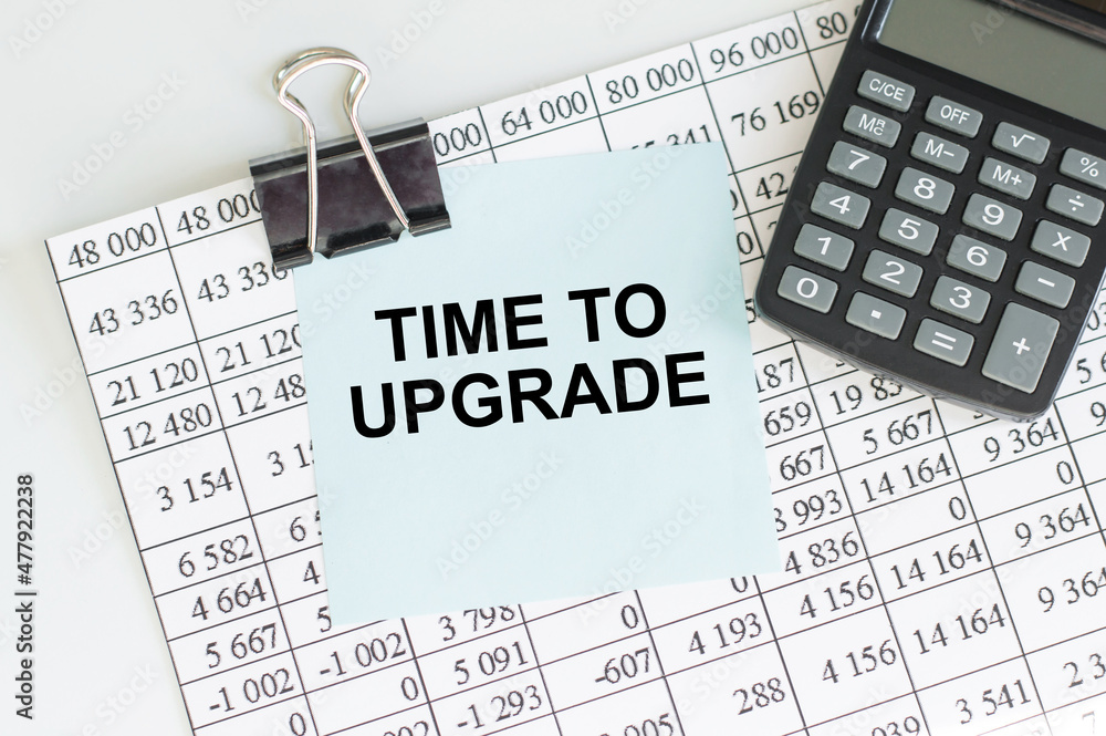 Poster text time to upgrade on a blue sticker on the background of a sheet with a table next to the calcula