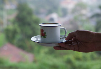 Hand holding a cup of coffee on a blur background