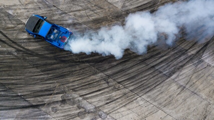 Aerial top view professional driver drifting car on asphalt road track with white smoke, Automobile race car drift on abstract asphalt road with black tire skid mark, View from above. - obrazy, fototapety, plakaty