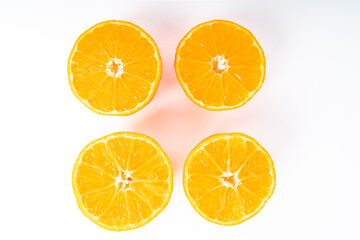 Four half orange colored tangerines in the middle of a white background