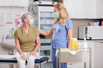 A Young White Female Medical Nurse Consults with an Elderly Senior Female Patient about Covid-19...