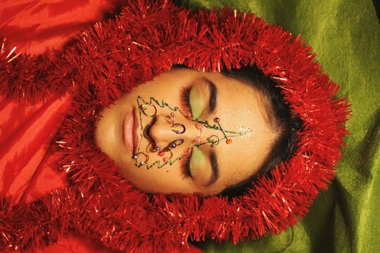 portrait of young woman with facepaint and piercings - a christmas tree drawing on face - new year celebration for 2022