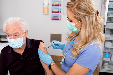 A Young White Female Medical Nurse Administering a Covid-19 Vaccine with a Syringe Needle to an...