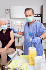 A White Male Medical Nurse Disposes of Syringe Needle Safely in Sharps Collector after...