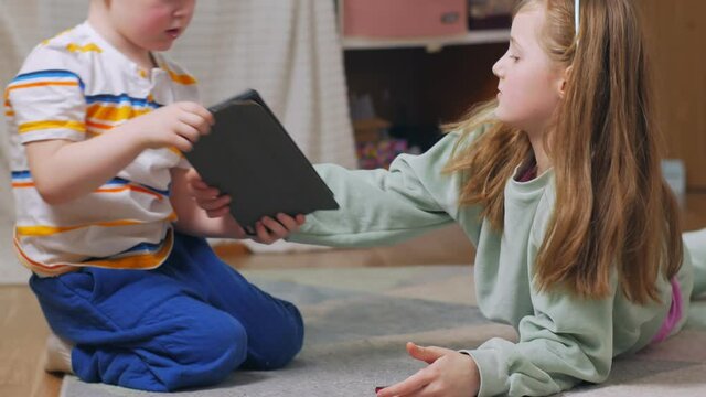 Children lie with gadgets on the floor