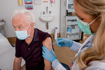 A Young White Female Medical Doctor Administering a Covid-19 Vaccine with a Syringe Needle to an...