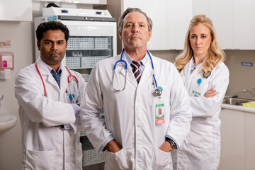A Professional Medical Team of Doctors. One Female Two Males with Generic ID Badges, Lab Coats and...