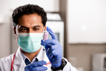 A Young Indian Male Medical Doctor Extracting a Covid-19 Vaccine Injection with a Syringe Needle...