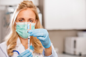 A Young Female Medical Doctor Extracting a Covid-19 Vaccine with a Syringe Needle Wearing Generic...