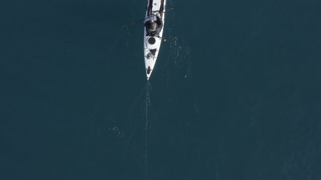 Single seat fishing canoe rowing at calm open sea water, Aerial view.