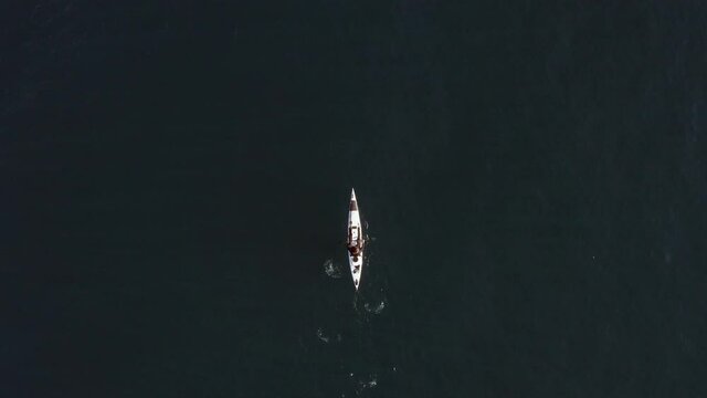 Single seat fishing canoe rowing at calm open sea water, Aerial view.