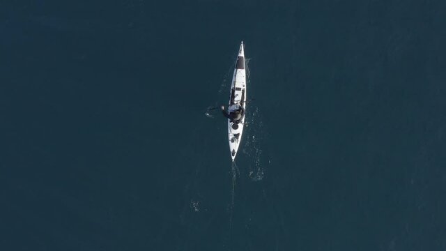 Single seat fishing canoe rowing at calm open sea water, Aerial view.
