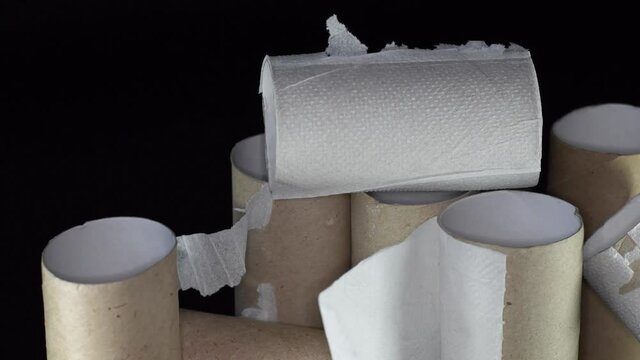 A pile of empty toilet paper rolls on a black background. Concept of scarcity of basic necessities during a crisis or pandemic.