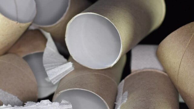 A pile of empty toilet paper rolls on a black background. Concept of scarcity of basic necessities during a crisis or pandemic.