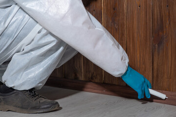 a man in protective clothing disinfects the house from household pests and insects