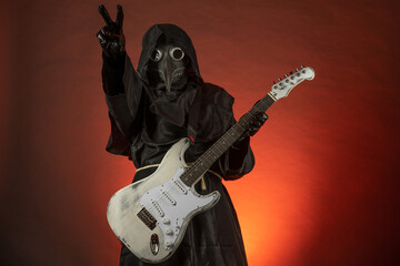 A man in a plague doctor costume plays the guitar emotionally on a red background