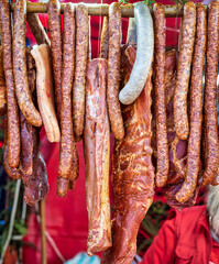 Many smoked Sausages and other pork meat products hanging from a stick at a food festival.