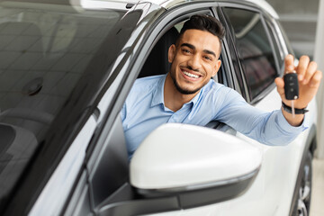 Happy arab man holding key from auto, buying car