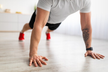 Closeup of mature male hands planking, wearing smartwatch while exercising in living room, crop