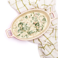 Delicious meatballs with spinach in a creamy sauce in baking dish on white background