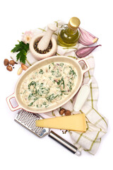 Delicious meatballs with spinach in a creamy sauce in baking dish on white background