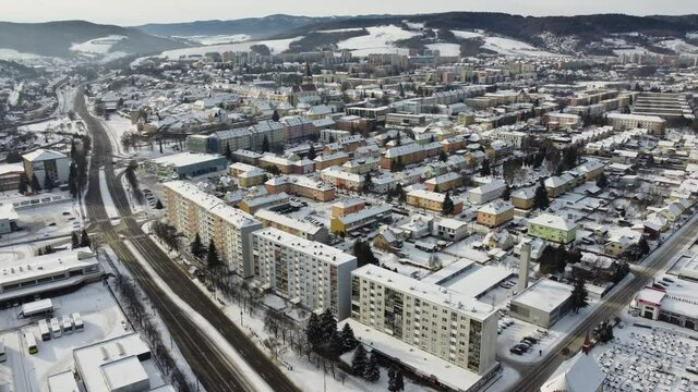 Aerial drone footage flying overlooking housing estates, public parks and commercial properties in a built up area in the small town of Bardejov in Slovakia during winter snowy sunrise, river Topla