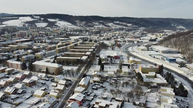 Aerial drone footage flying overlooking housing estates, public parks and commercial properties in a built up area in the small town of Bardejov in Slovakia during winter snowy sunrise, river Topla