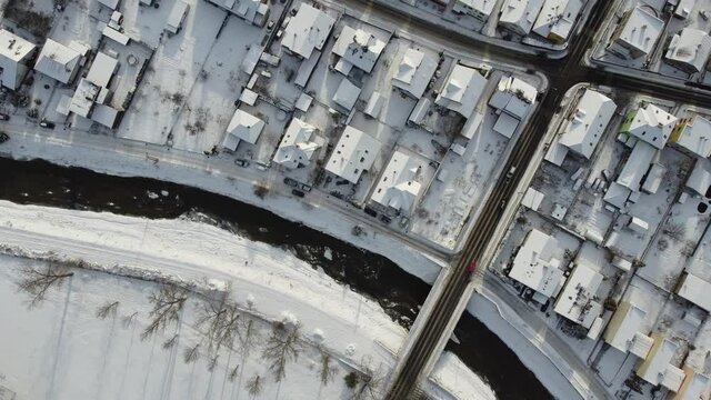 Aerial drone footage flying overlooking housing estates, public parks and commercial properties in a built up area in the small town of Bardejov in Slovakia during winter snowy sunrise, river Topla