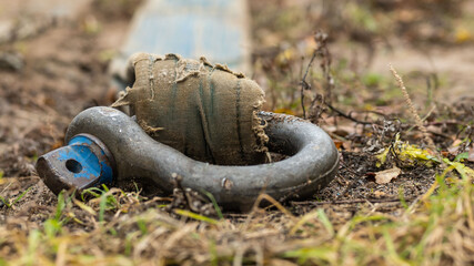 a heavy iron link for lifting loads lies abandoned on the ground. background picture. selective focus.