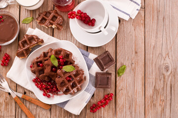 Waffles with chocolate topping, red currant and hazelnuts.
