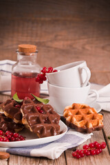 Waffles with chocolate topping, red currant and hazelnuts.