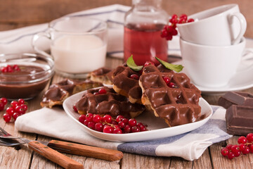 Waffles with chocolate topping, red currant and hazelnuts.