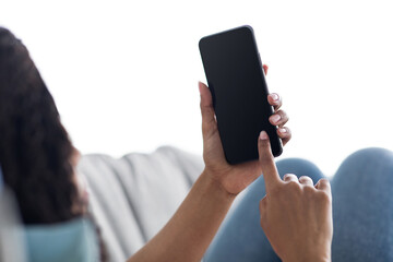 Mockup, blank screen of cell phone. Woman hand texting, using mobile on sofa at home