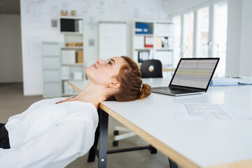 Laid back young businesswoman relaxing with head on table
