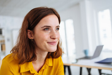 Happy young woman sitting daydreaming with a smile of pleasure
