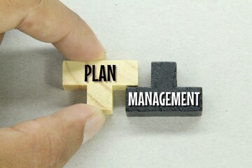 fingers holding a wooden puzzle with the word plan management