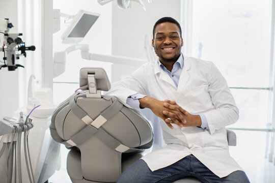 Portrait Of Young Black Dentist Doctor Sitting At Workplace In Modern Clinic