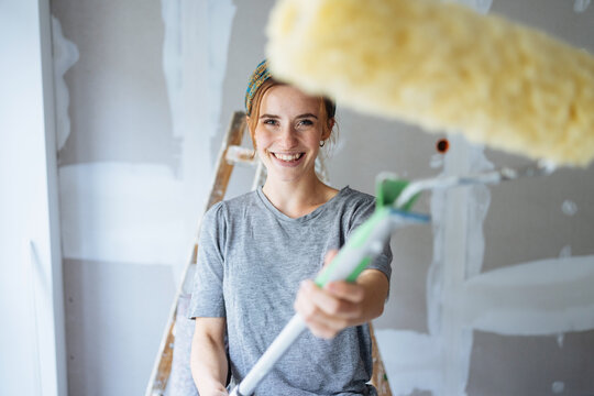 Happy smiling young woman brandishing a paint roller