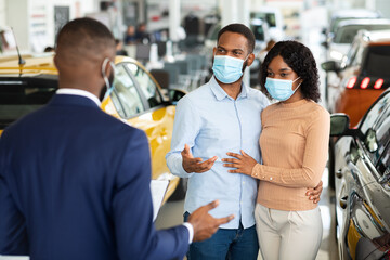 Young African American Family In Medical Masks Buying Car In Dealership Office